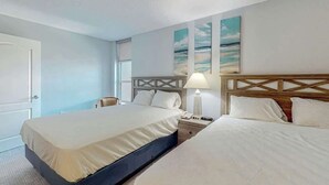Quarto de hotel com uma cama grande, mesas de cabeceira, uma luminária e uma obra de arte na parede.