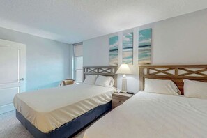 Ein Hotelzimmer mit einem großen Bett, Nachttischen, einer Lampe und Bildern an der Wand.