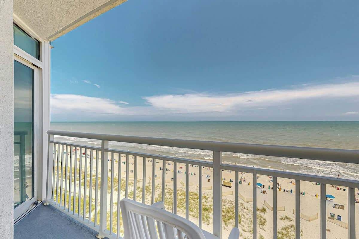A balcony with a view of a beach and ocean.