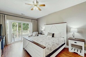 A bedroom with a bed, bedside tables, a ceiling fan, and a window with curtains. - Cypress Point Retreat 202 (Myrtle Beach)