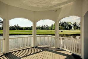 Eine überdachte Veranda mit Blick auf einen Golfplatz und ein Gewässer.