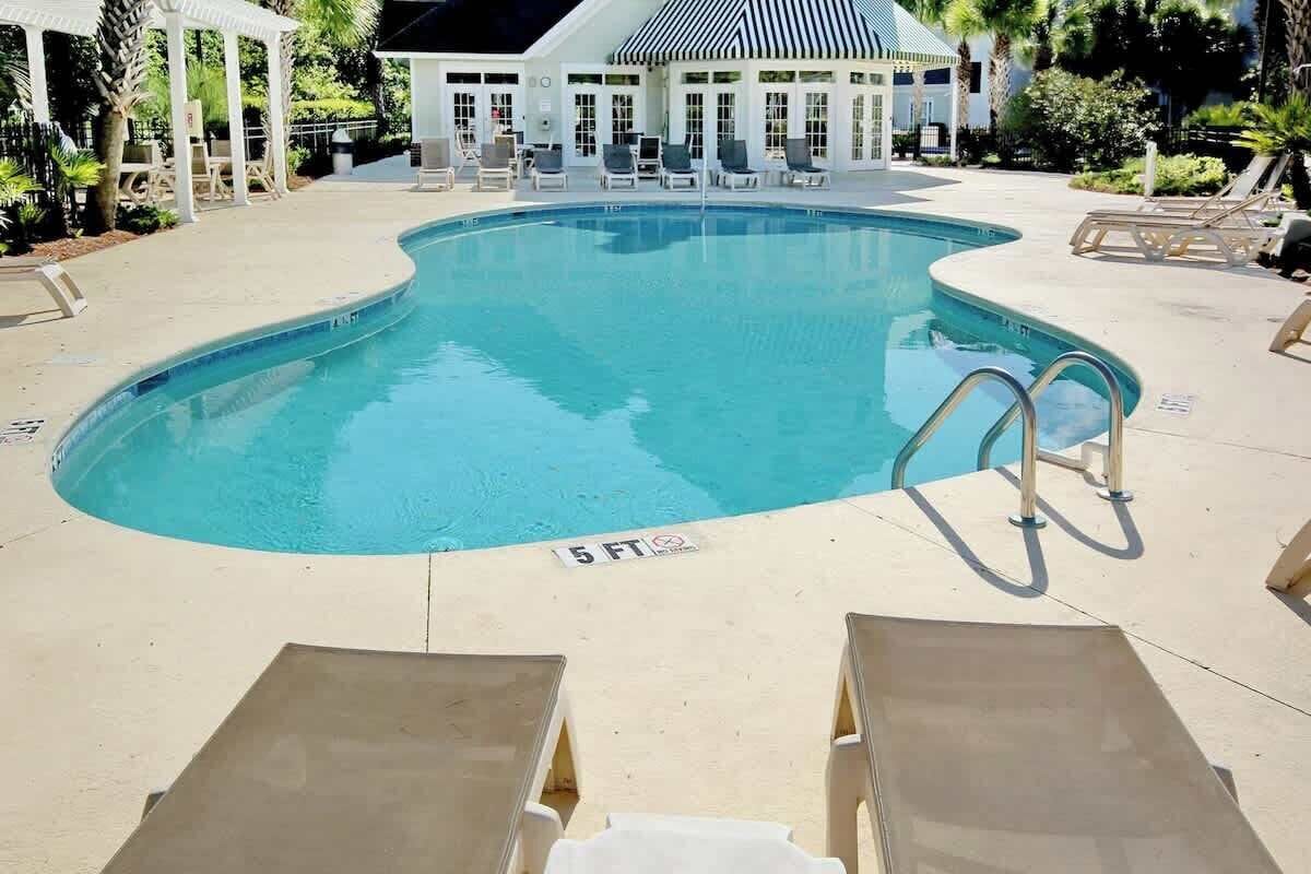 A swimming pool with lounge chairs and a covered seating area.