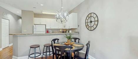A dining area with a round table, chairs, and a chandelier.