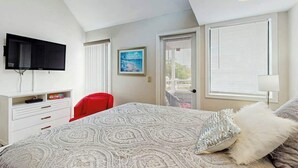A bedroom with a bed, a television, a desk, and a chair. - Arcadian Dunes 18-370 (Myrtle Beach)