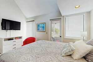 Ein Schlafzimmer mit einem Bett, einem Fernseher, einem Schreibtisch und einem Sessel.