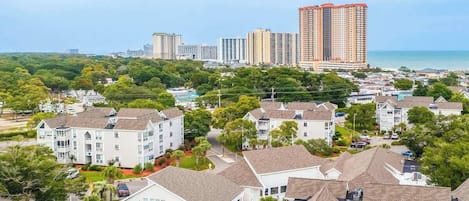 A residential area with multiple-story buildings, a swimming pool, and a view of the ocean.