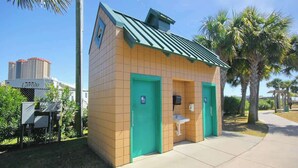 A small, single-story building with a green roof and two doors, one of which has a wheelchair accessibility sign. - Arcadian Dunes 18-370 (Myrtle Beach)