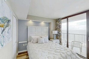 Ein Schlafzimmer mit Bett, Nachttisch, Fenster mit Aussicht und Balkon mit Sitzgelegenheiten.