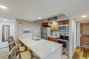 A modern kitchen with a central island, stainless steel appliances, and wooden cabinets. - Sands Ocean Club 1629 (Myrtle Beach)