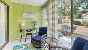 Een kamer met een groene wand, een tafel met een lamp, een stoel en een bank.