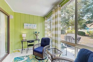 Ein Zimmer mit grüner Wand, einem Tisch mit Lampe, einem Stuhl und einem Sofa.