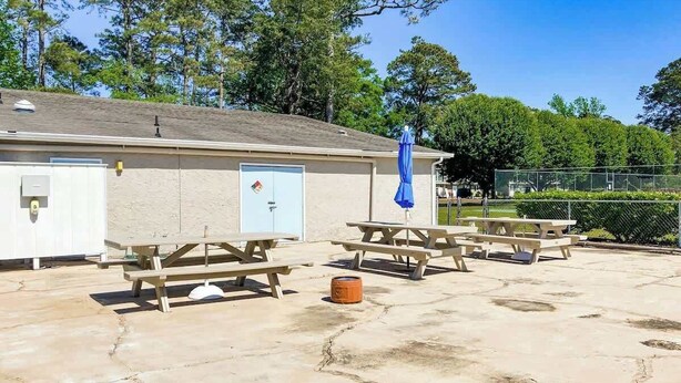 Een gebouw met picknicktafels en een overdekt gedeelte, omringd door bomen.