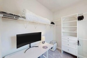 A bedroom with a bed, a desk, a TV, a wardrobe, and a shelf with clothes. - Double Eagle Escape Retreat (North Myrtle Beach)