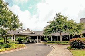 A covered outdoor area with a curved driveway leading to a building with a pitched roof. - Double Eagle Escape Retreat (North Myrtle Beach)