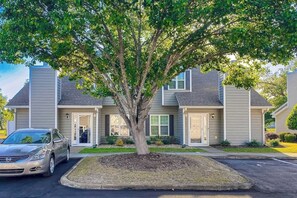 A two-story building with a tree in front, a parked car, and a clear sky. - Fairway Oaks Unit 24B (North Myrtle Beach)