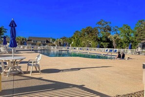 A swimming pool area with lounge chairs and umbrellas, surrounded by a fence and trees. - Fairway Oaks Unit 24B (North Myrtle Beach)
