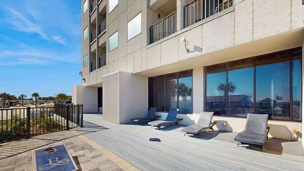 A modern building with a rooftop deck featuring lounge chairs and a shuffleboard table. - Renaissance Tower 908 (Myrtle Beach)