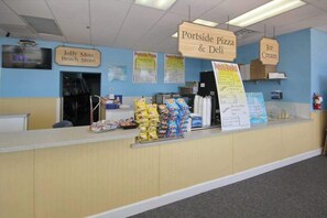 Eine Theke mit Schildern für 'Jolly Mon Beach Store', 'Portside Pizza & Deli' und 'Ice Cream'.
