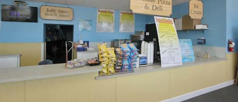 A counter with signs for 'Portside Pizza & Deli' and 'Jolly Mon Beach Store'.