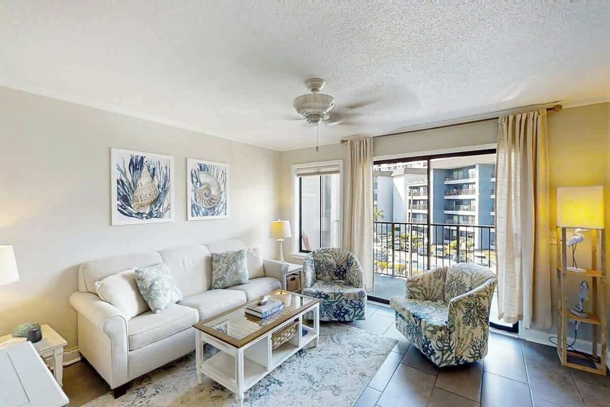 A living room with a sofa, armchair, coffee table, and artwork on the wall.