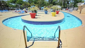 Un espace piscine de forme circulaire, avec un escalier pour y accéder et des chaises longues.