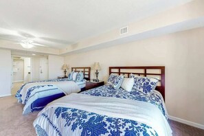 Une chambre d’hôtel avec deux lits, chacun doté d’une tête de lit, de tables de chevet, de lampes et d’un miroir.