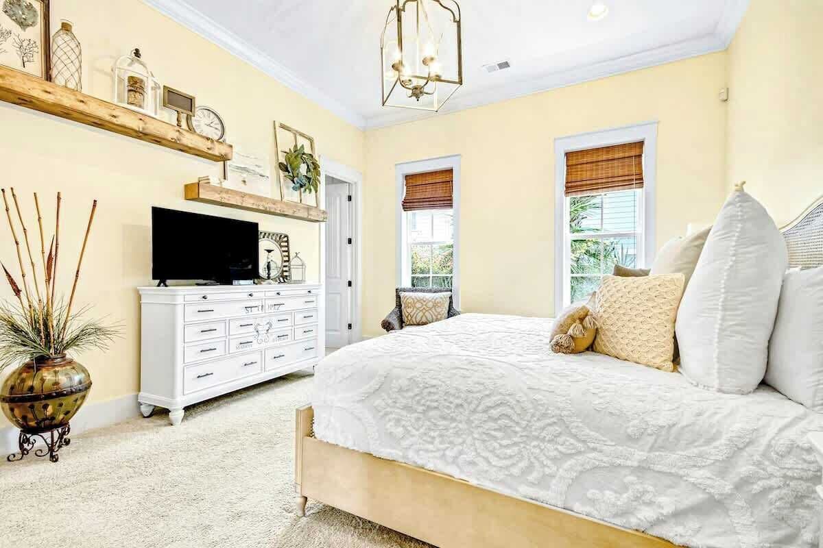 A bedroom with a bed, dresser, television, and decorative items.