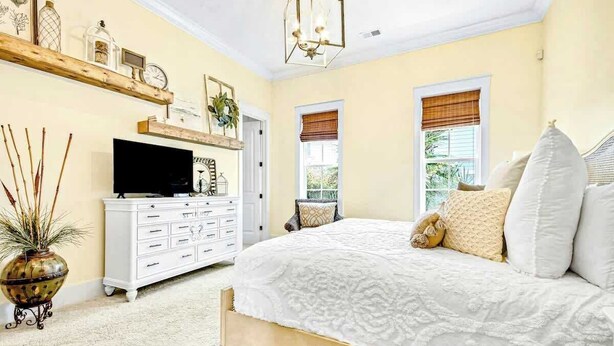 A bedroom with a bed, dresser, television, and decorative items. - Barefoot Livin' Retreat (North Myrtle Beach)