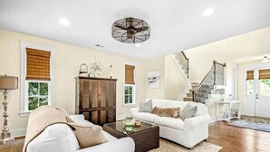 A living room with a white sofa, a coffee table, and a large wooden cabinet. - Barefoot Livin' Retreat (North Myrtle Beach)