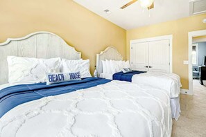 Een slaapkamer met twee bedden, een wit hoofdbord en een beige wand.