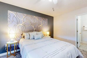 Ein Schlafzimmer mit einem Bett, Nachttischlampen, einer Wandverkleidung und einer Tür.