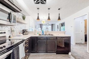 A modern kitchen with dark cabinetry, a dishwasher, and a built-in oven.
