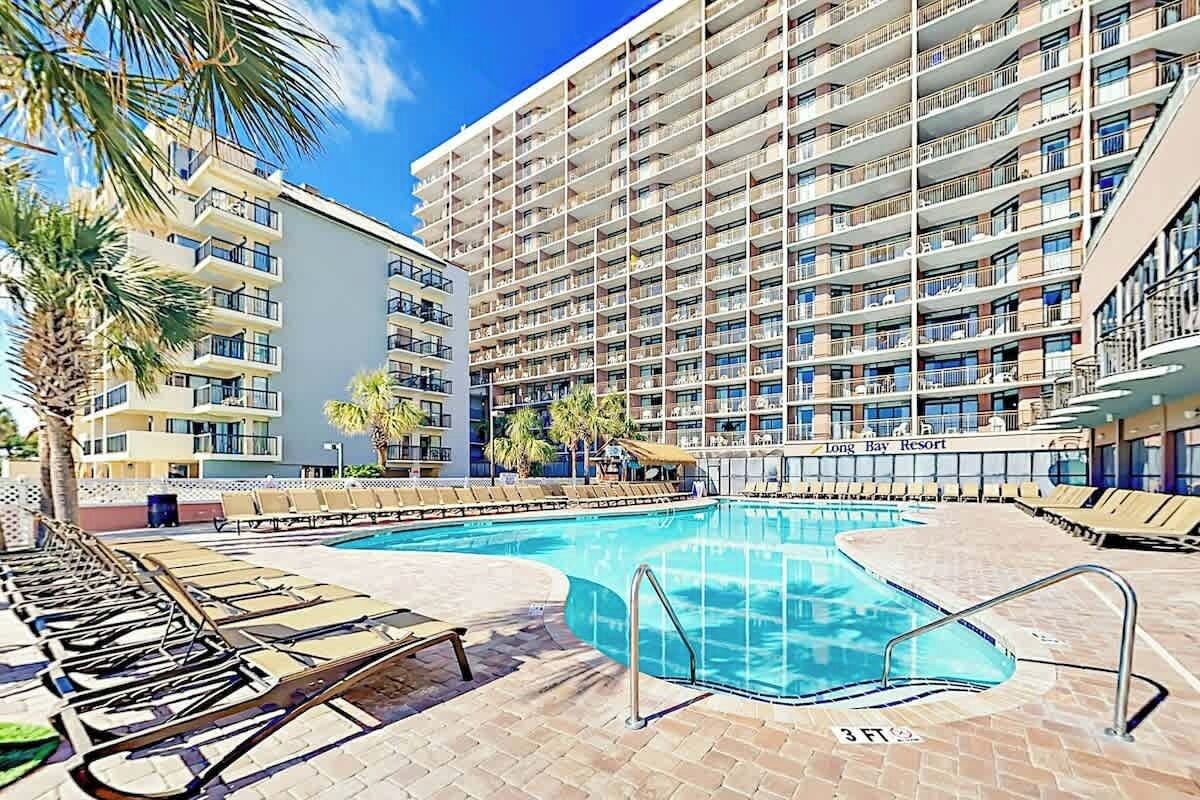 A hotel with a swimming pool, multiple balconies, and sun loungers.
