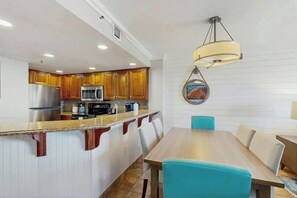 A modern kitchen with wooden cabinets, stainless steel appliances, and a central island with seating. - Cast a Wave, Unit 352 (Myrtle Beach)