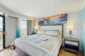 Une chambre d’hôtel avec un lit, un tableau, une table de chevet et une vue sur l’extérieur.
