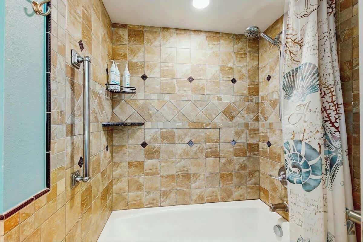 Un baño con bañera, ducha y paredes de azulejos.