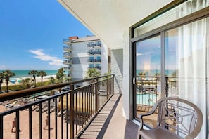 Uma varanda com vista para uma praia e uma piscina.