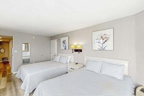 Ein Hotelzimmer mit zwei Betten, einem Nachttisch, einer Lampe und einem Spiegel.