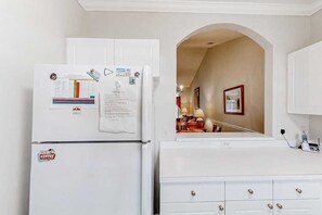 Eine Küche mit einem weißen Kühlschrank, einer weißen Arbeitsplatte und einem weißen Schrank.