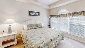 A bedroom with a bed, a nightstand, a lamp, a ceiling fan, a window with blinds, and a wall-mounted picture. - Cypress Bend Unit 434 (North Myrtle Beach)