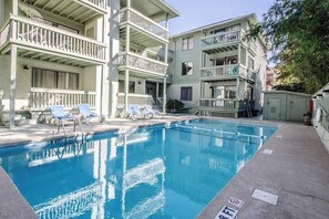 A swimming pool with lounge chairs and a multi-story building with balconies. - The Dry Dock, Unit 302 (Myrtle Beach)