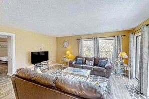 A living room with a sofa, a coffee table, a television, and two lamps. - The Dry Dock, Unit 302 (Myrtle Beach)