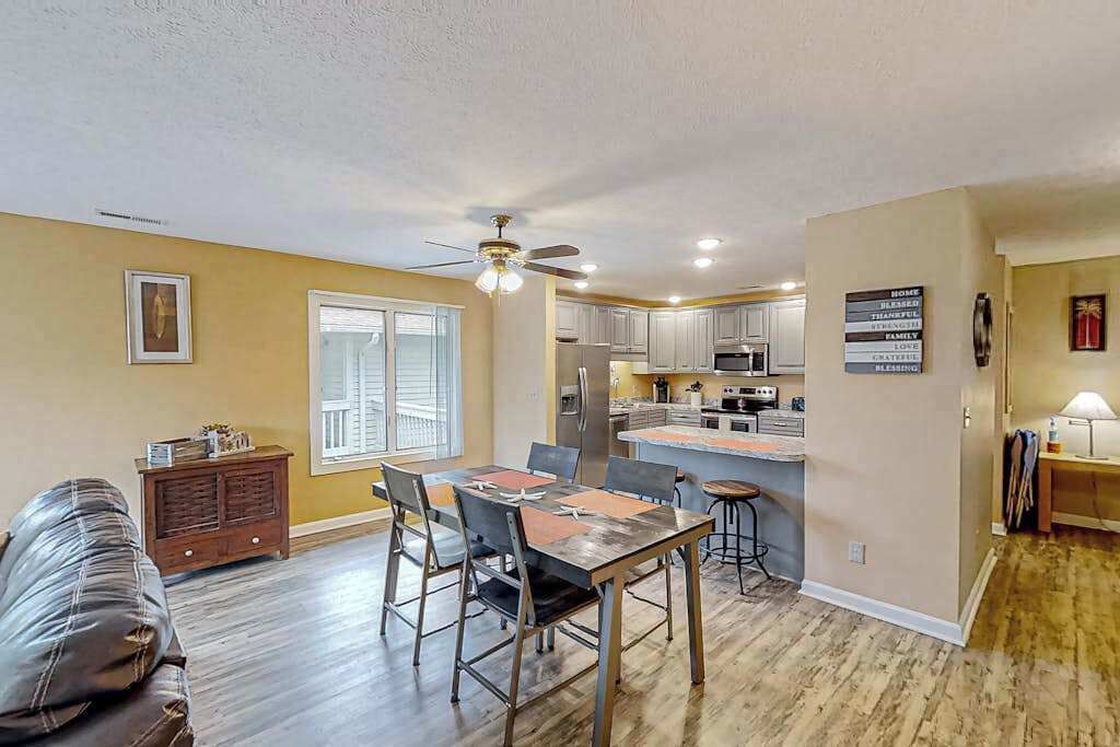A spacious living room with a dining area, a kitchen, and a ceiling fan.