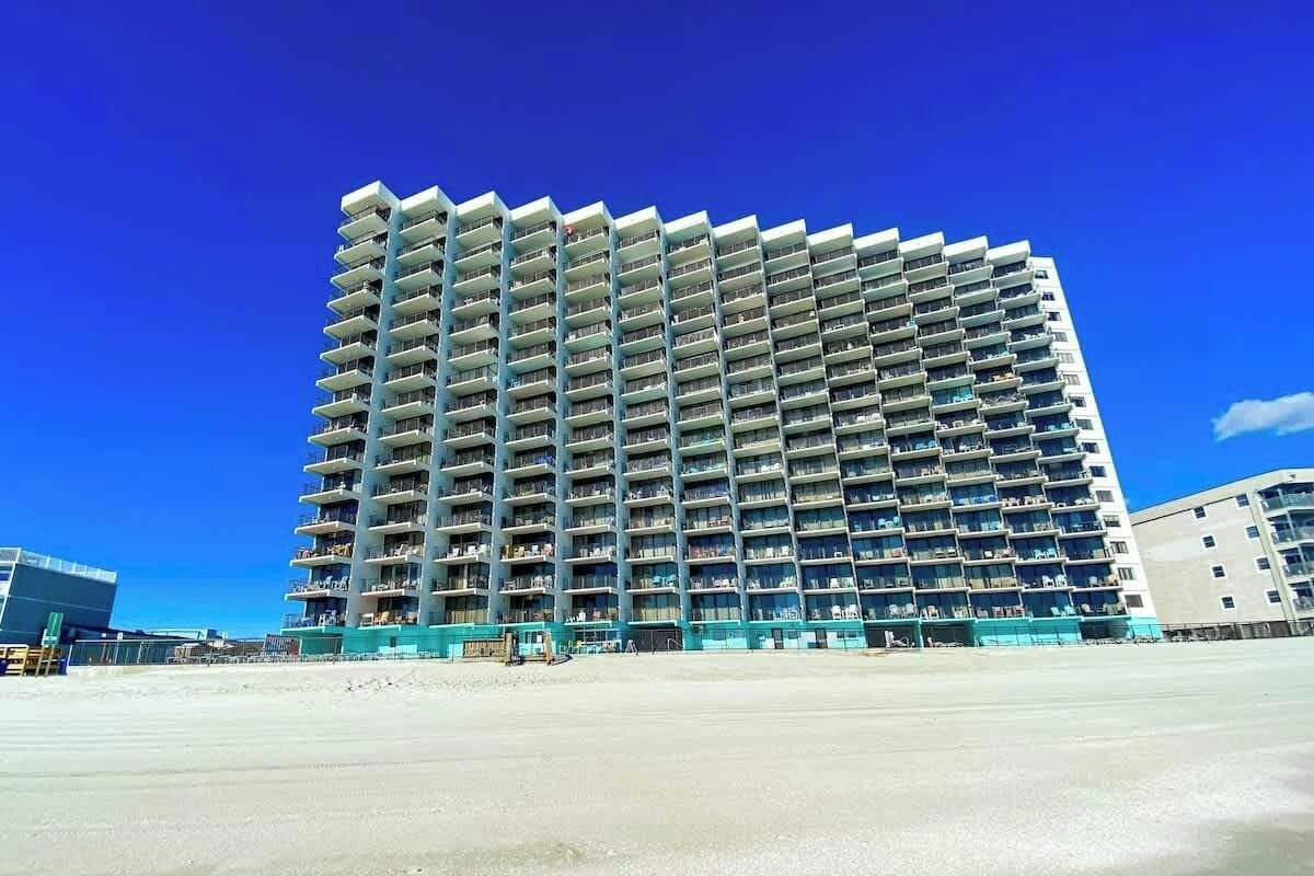 A multi-story hotel with balconies, a flat roof, and a clear blue sky.