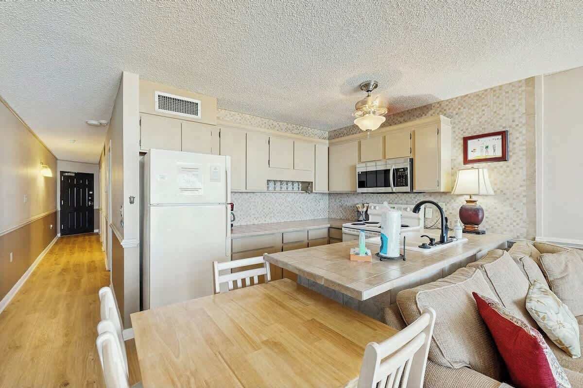 A compact kitchen with a dining area, a microwave, a refrigerator, and a ceiling fan.