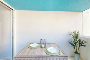 A small dining table with two plates and a candle, set against a plain wall with a potted plant. - Club Wyndham Unit 521 (North Myrtle Beach)