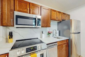 A kitchen with wooden cabinets, a microwave, a stove, a dishwasher, and a refrigerator. - Club Wyndham Unit 521 (North Myrtle Beach)