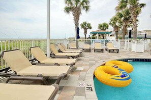 A poolside area with lounge chairs and a pool with inflatable rings. - Club Wyndham Unit 521 (North Myrtle Beach)