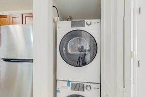 A compact laundry room with a top-loading washing machine and a stainless steel refrigerator. - Club Wyndham Unit 521 (North Myrtle Beach)