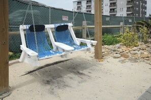 A swing chair with a blue net, a white bench, and a chain. - Club Wyndham Unit 521 (North Myrtle Beach)